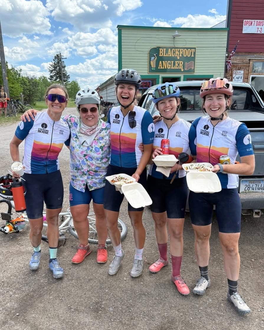 Cycling House riders wearing sunset kits during a food stop
