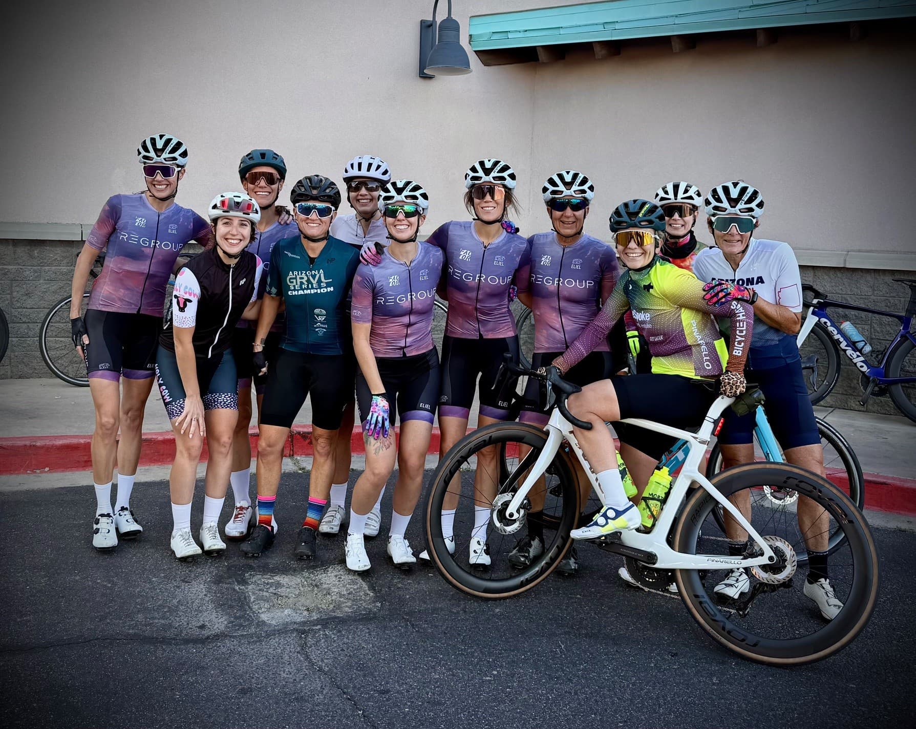 The full group of cyclists together with their bicycles, wearing Regroup kits and other cycling apparel
