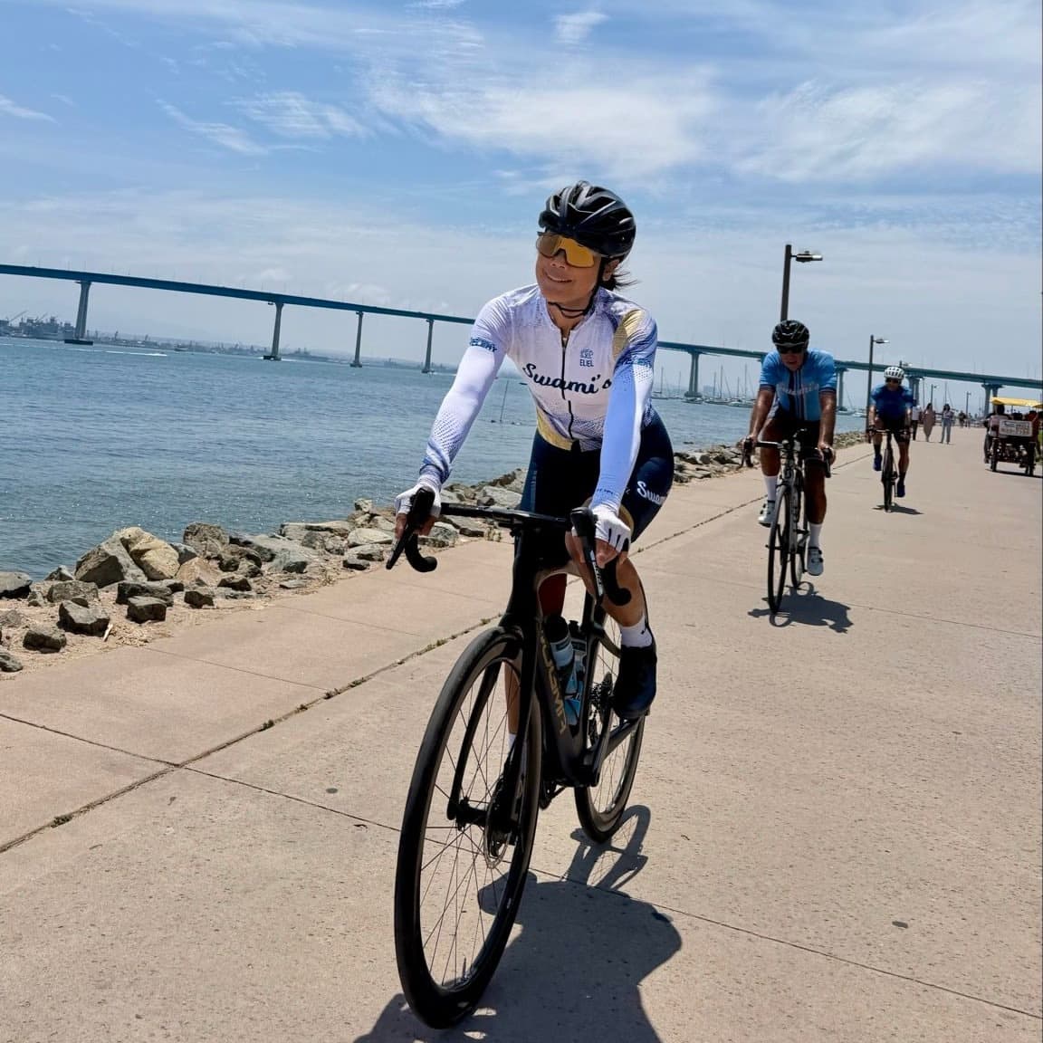 Cyclist wearing the white Swami’s summer design beside the bay
